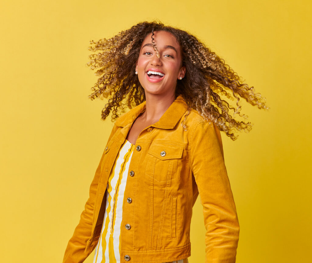 A young woman with curly hair in a happy mood